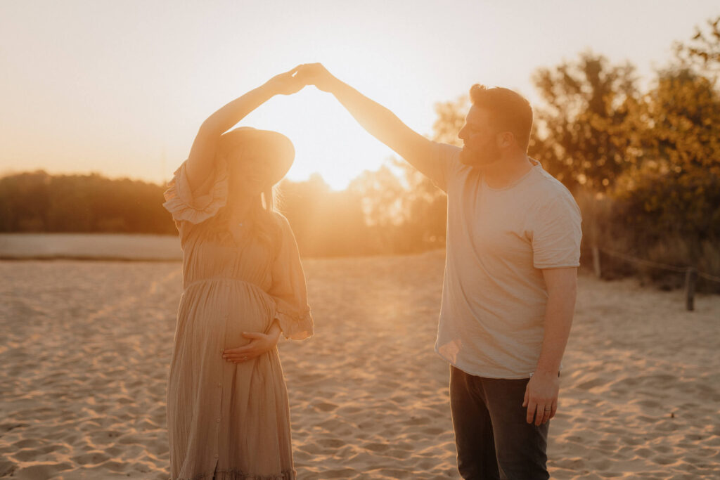 babybauchshooting boberger duenen im sonnenuntergang, schwangere und partner tanzen