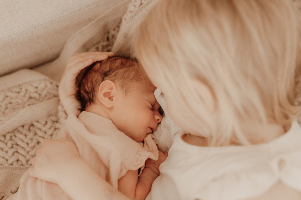 newbornshooting, baby liegt im arm der grossen schwester und schlaeft