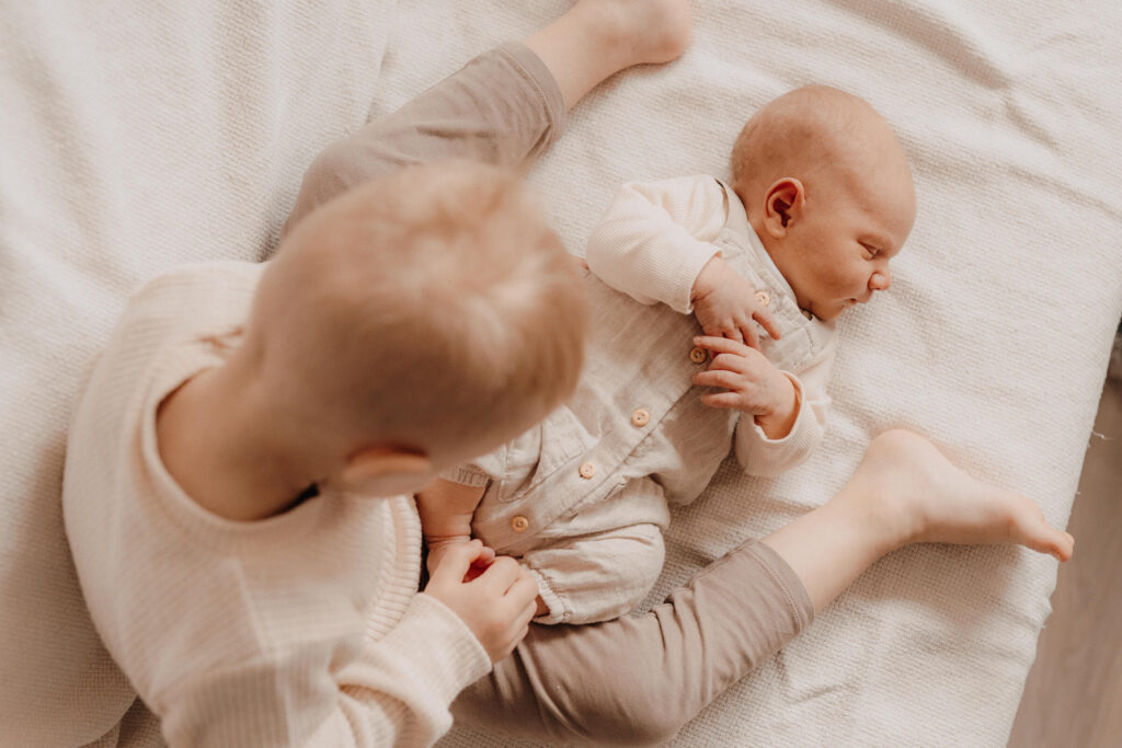 newbornshooting, baby liegt vor grossem bruder und schlaeft