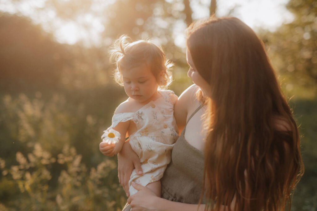 mama kind shooting, mama hat kind auf dem arm und gucken sich eine blume an
