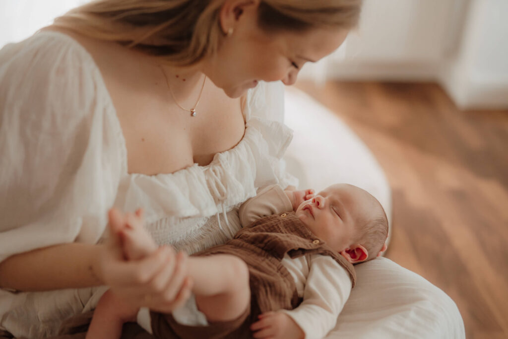 newbornshooting, baby liegt auf mamas schoß, baby schlaeft