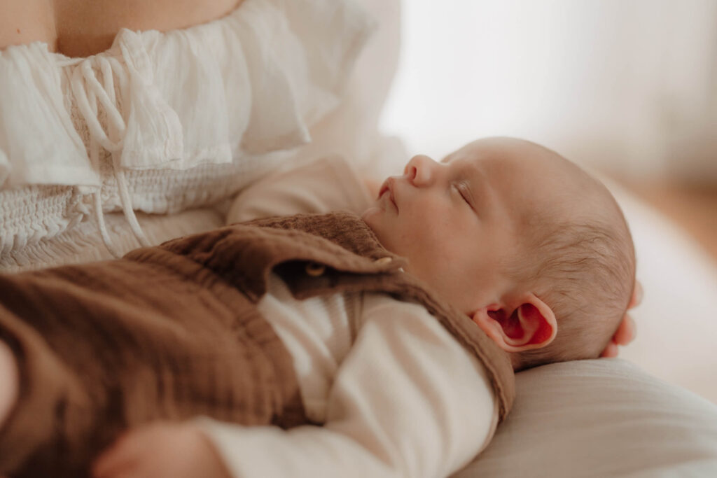 newbornshooting, baby liegt auf mamas schoß, baby schlaeft, nahaufnahme baby
